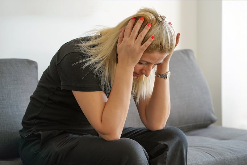 Woman leaning over on a couch in distress.