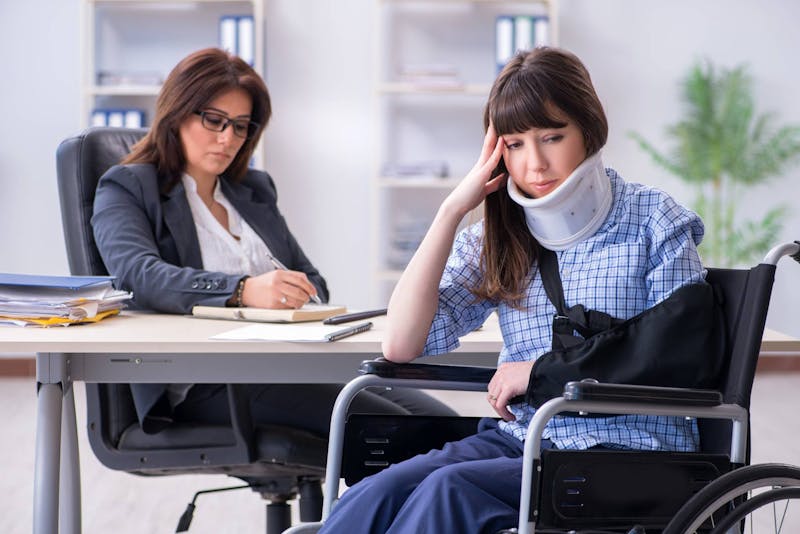 Woman sitting in a wheelchair holding her head.