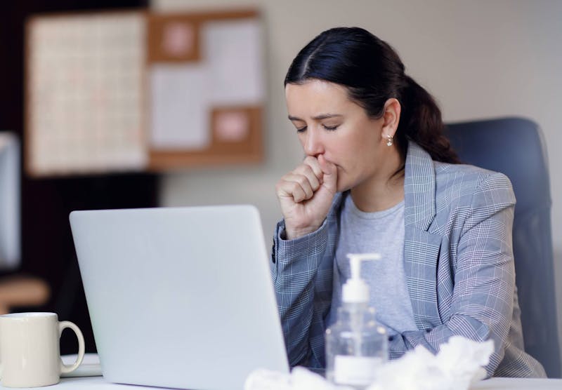 Woman coughing while working at a computer.