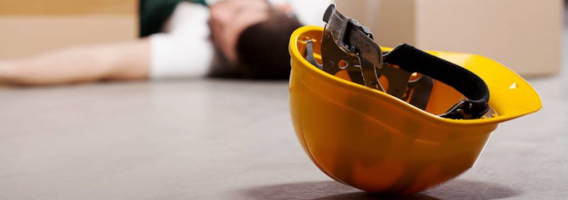Man laying on the floor next to a hard hat.