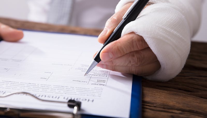 Person with an injured hand filling out a form.