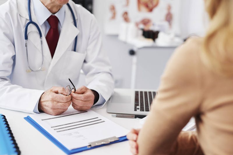 Woman talking to a doctor across a desk.