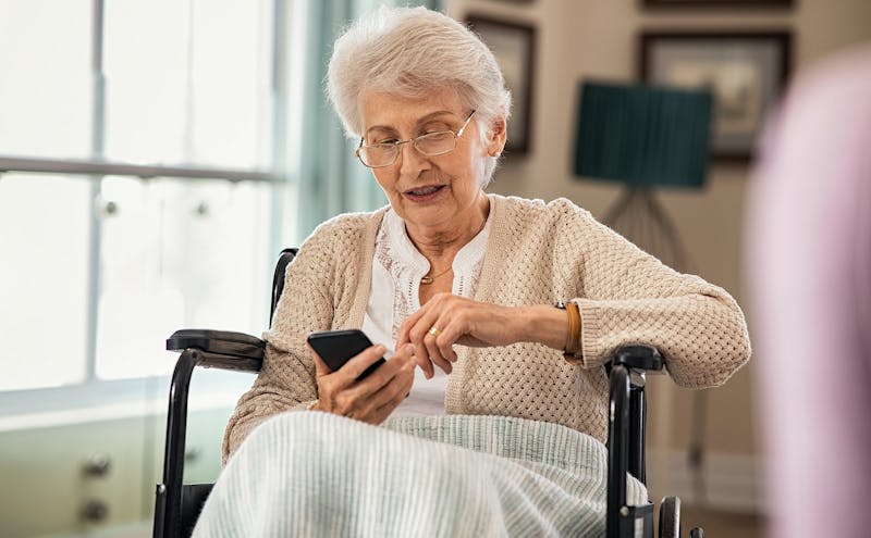 Woman sitting in a wheelchair typing on her phone.