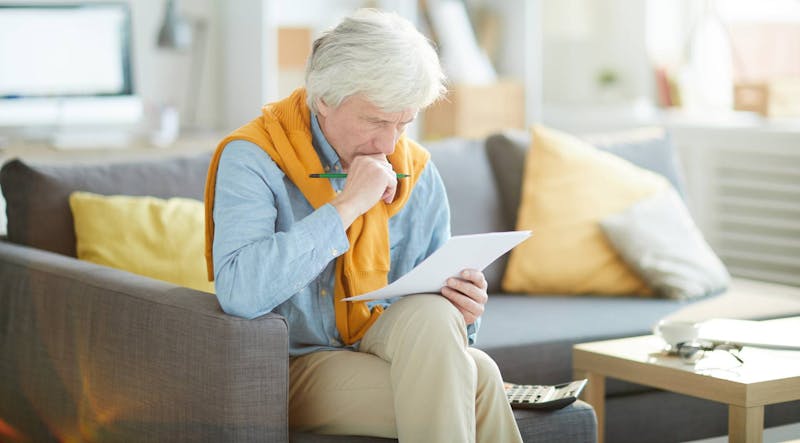 Man sitting down and reading papers in detail.
