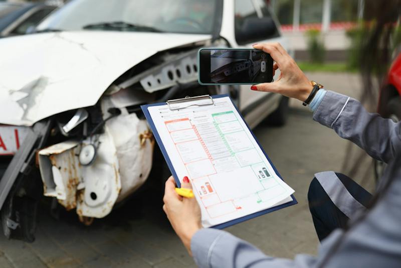 Woman taking photos and notes on car accident