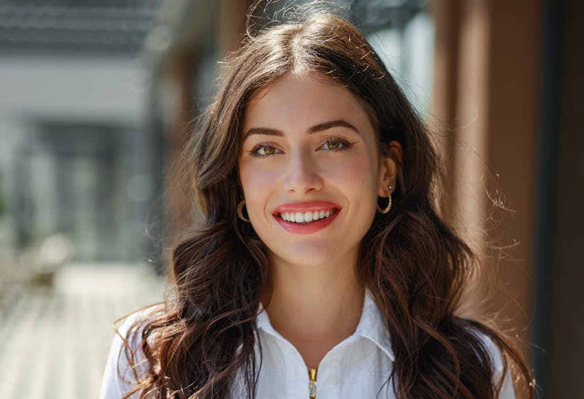 Woman with long brown curly hair smiling