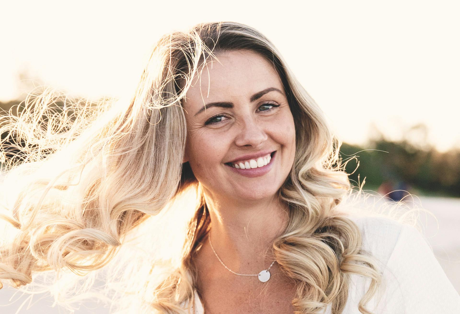Woman with long curly blonde hair smiling