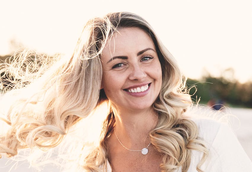 Woman with long curly blonde hair smiling