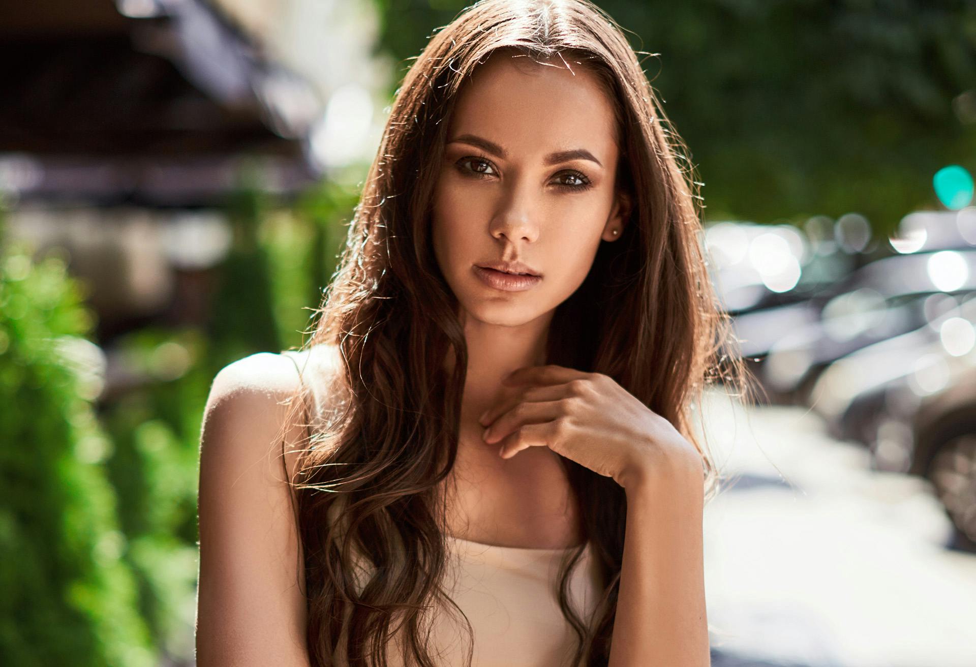Woman with long brown hair and a full face of makeup outside