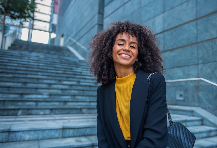 Woman with very curly hair outside standing on steps