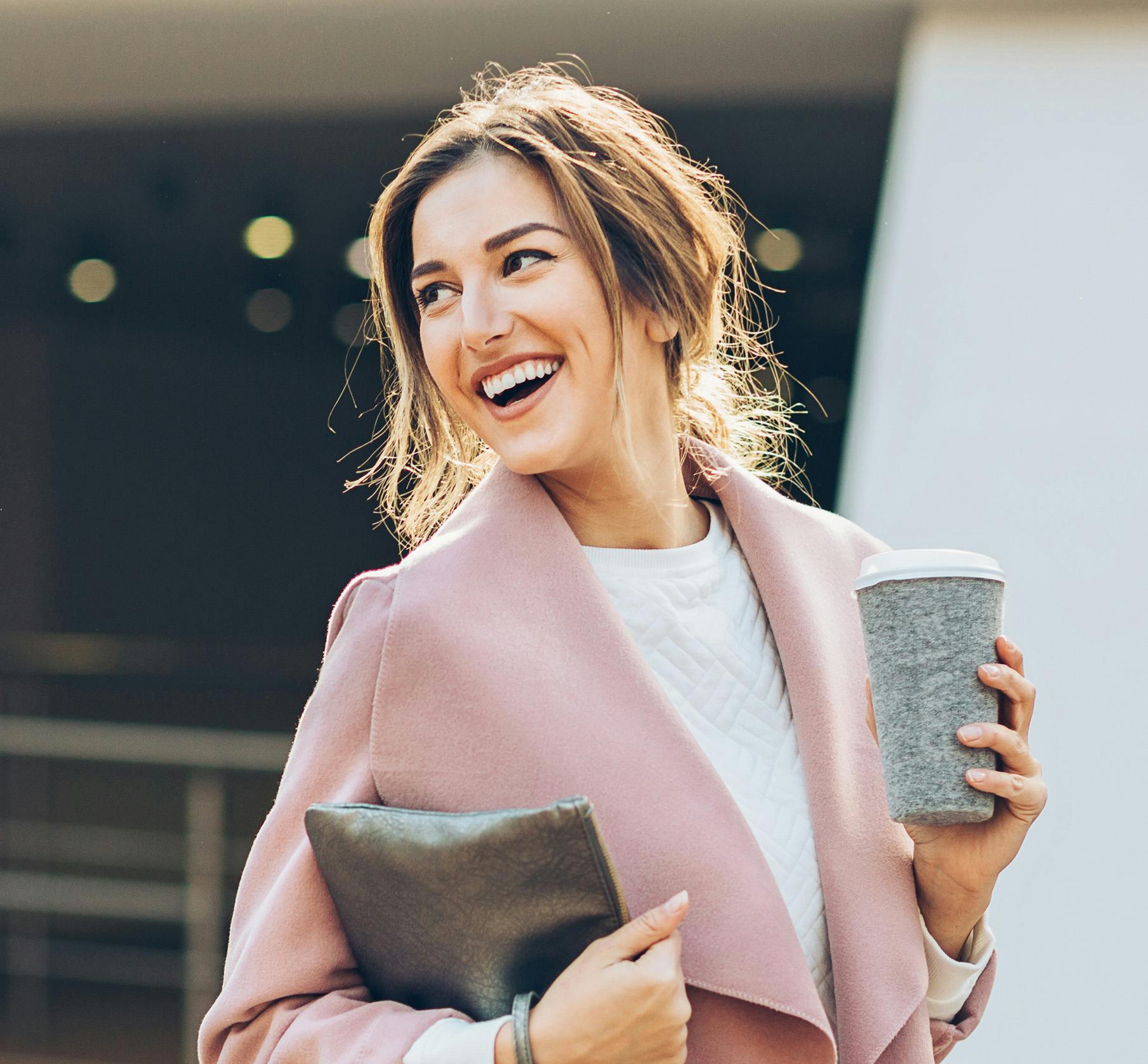 Woman in pink sweater holding a coffee