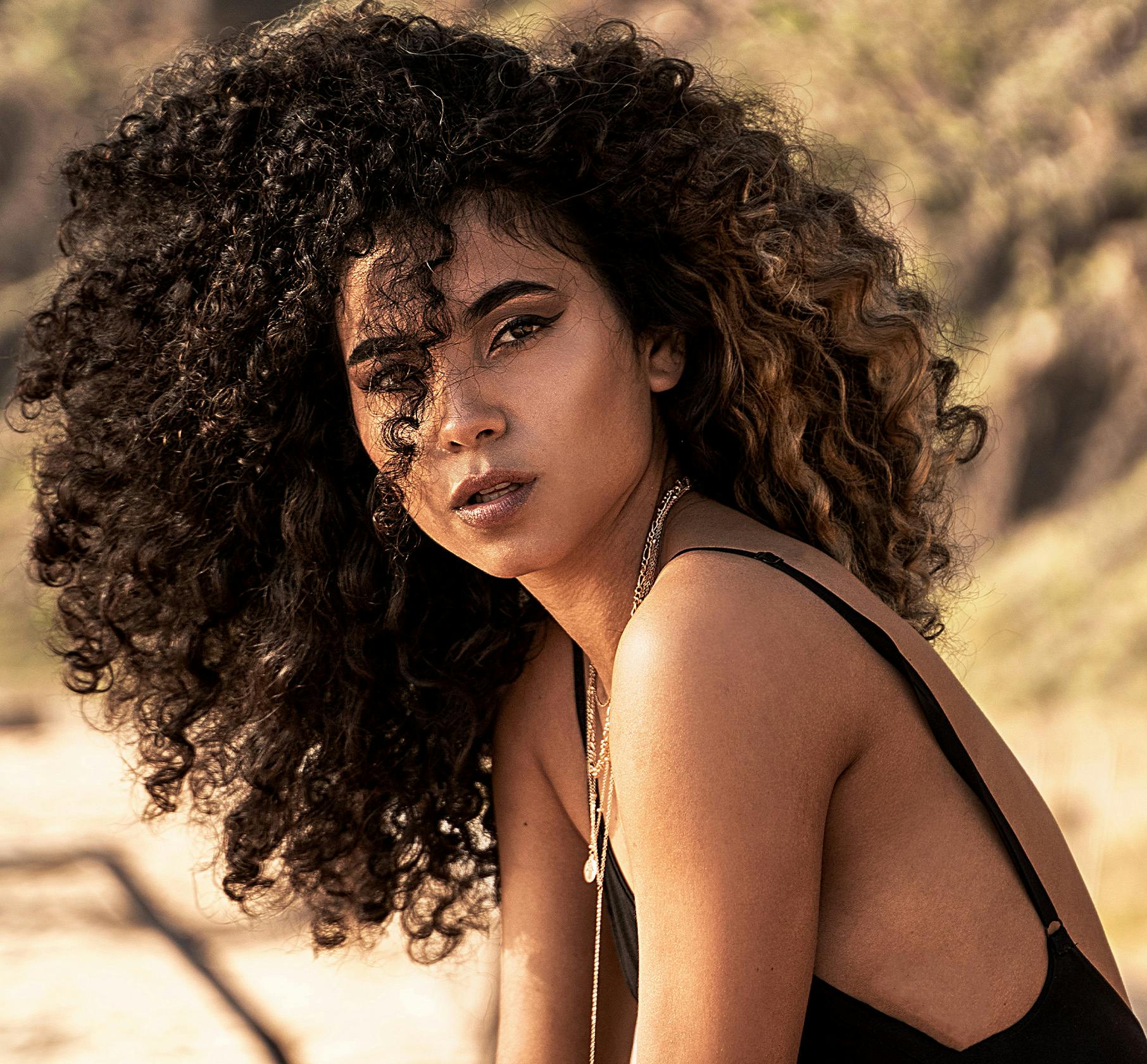 Woman with curly hair sitting on beach