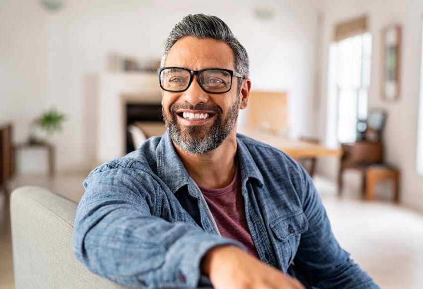 Man with salt and pepper hair wearing glasses and smiling