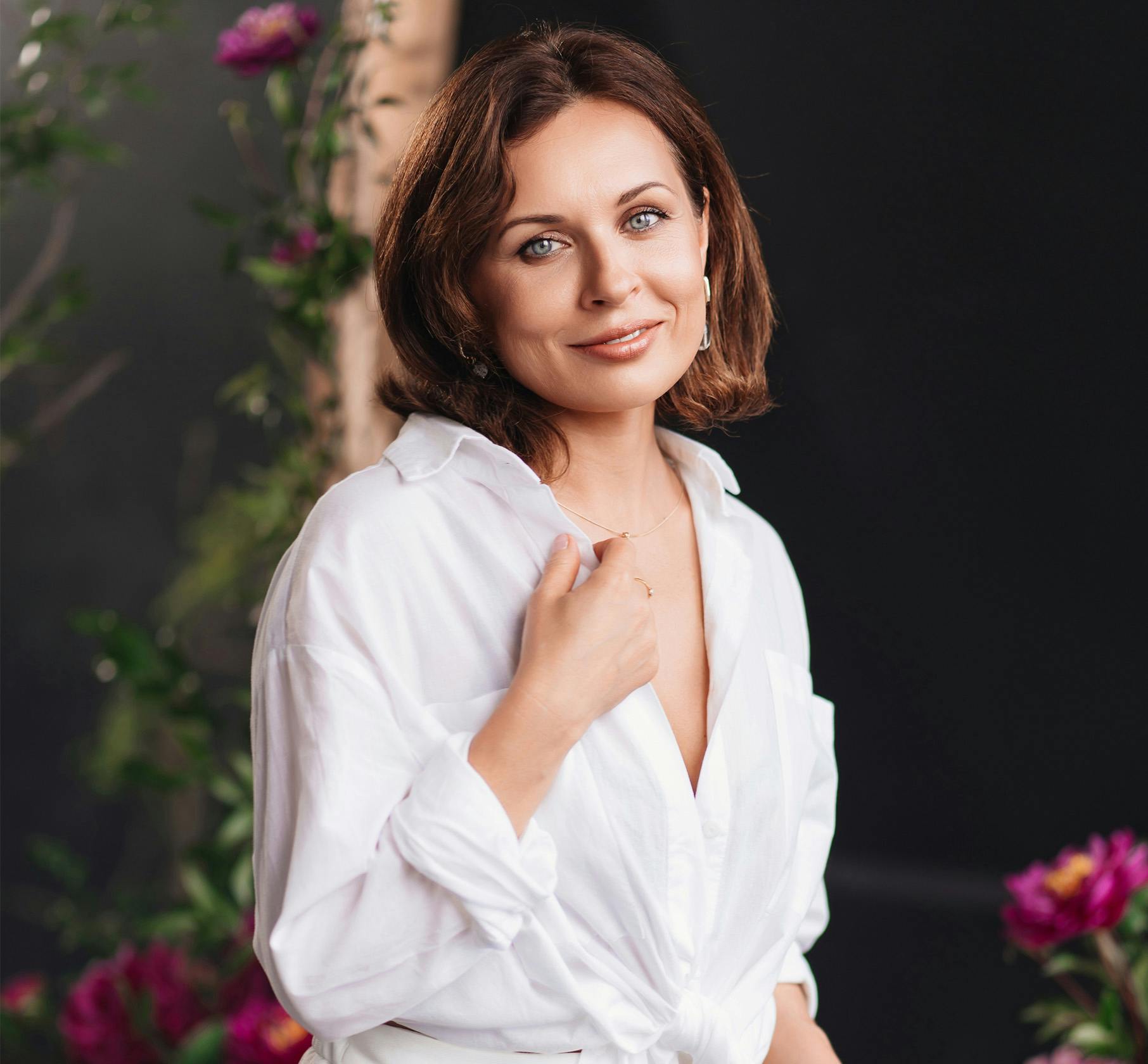 Woman in a white top with her hand against her shirt