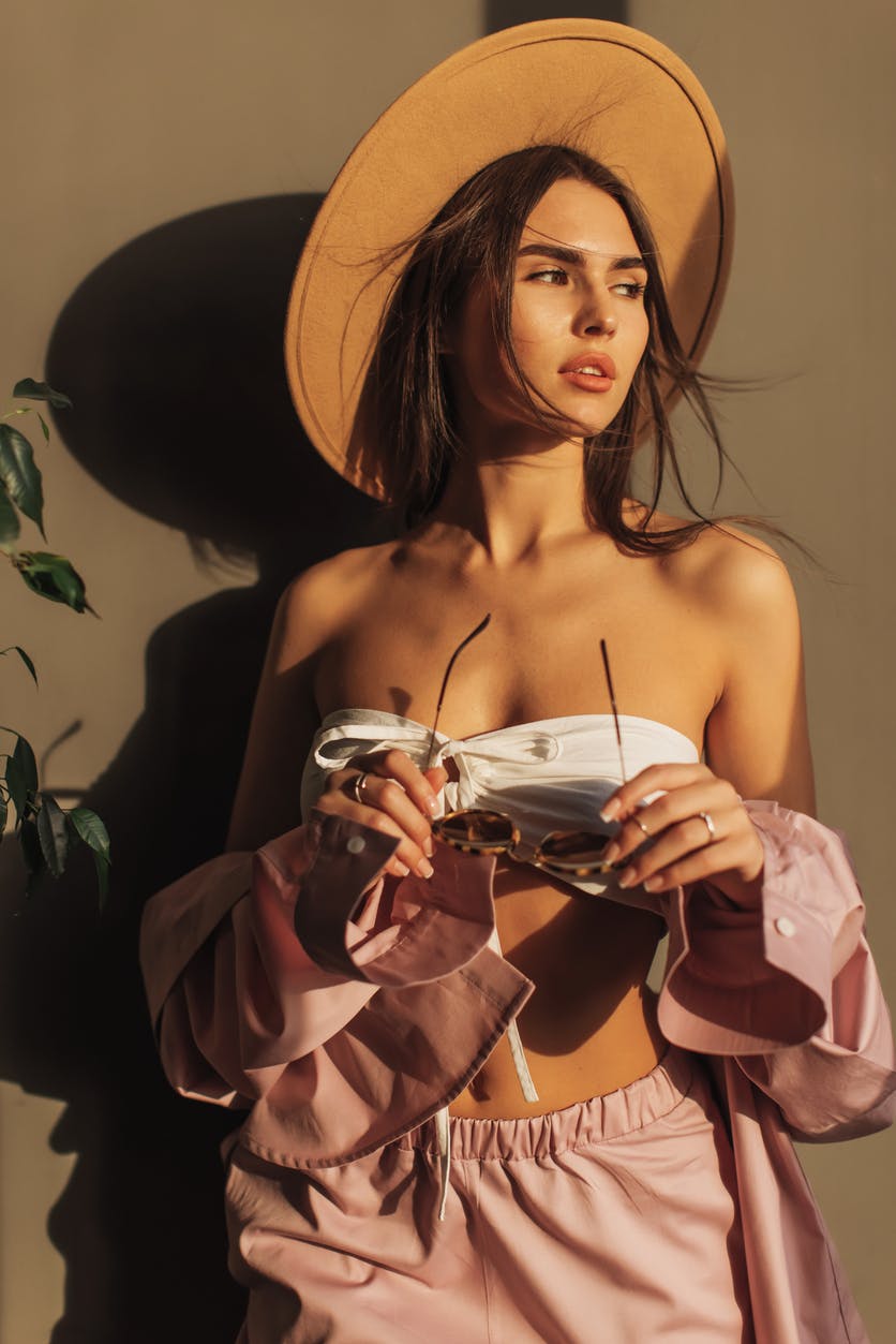 Woman in a hat holding her sunglasses