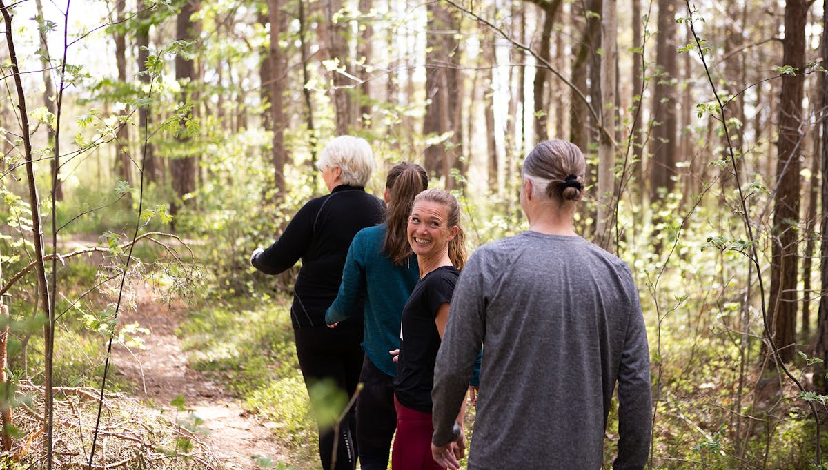 Fyra av Midagons medarbetare är ute och promenerar tillsammans på en stig i skogen.