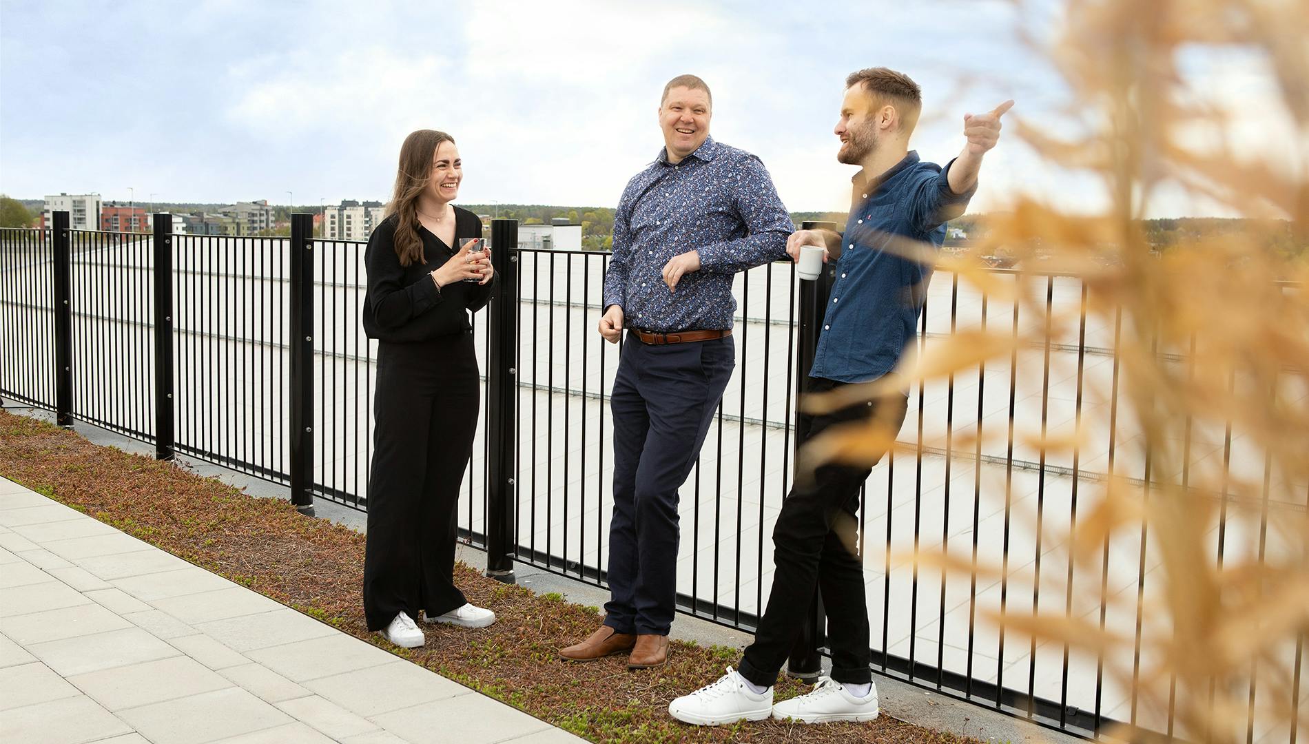Tre kollegor står och pratar med varandra på takterrassen på Midagons Örebrokontor.