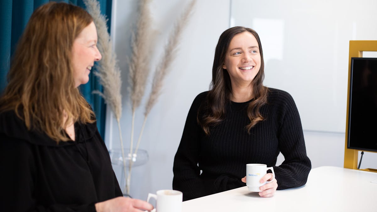 Kollegor som sitter och tar en kaffe på Midagons kontor i Örebro. På bilden är fokus på en kollega som har en kaffekopp i handen och ler.